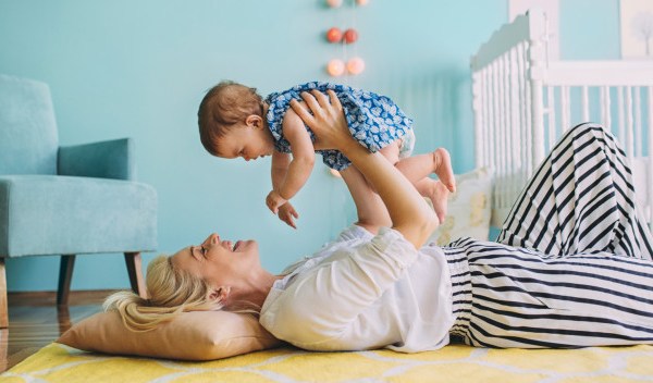 La niñera acostada en el suelo y sosteniendo a una niña