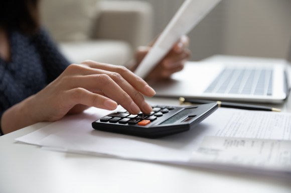 Close up of someone using a calculator while reading a document