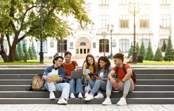 Group of college students sitting on steps on campus.