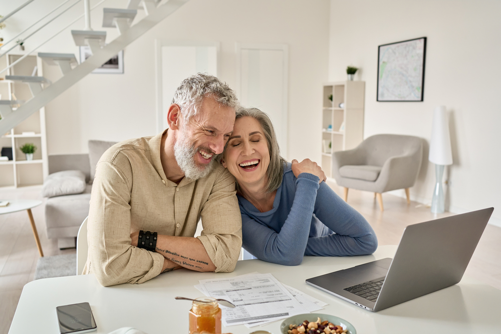 Happy retired couple sitting at the table looking over finances.