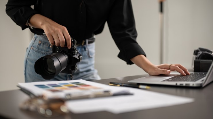 Professional photographer holding a camera and checking images on a laptop.