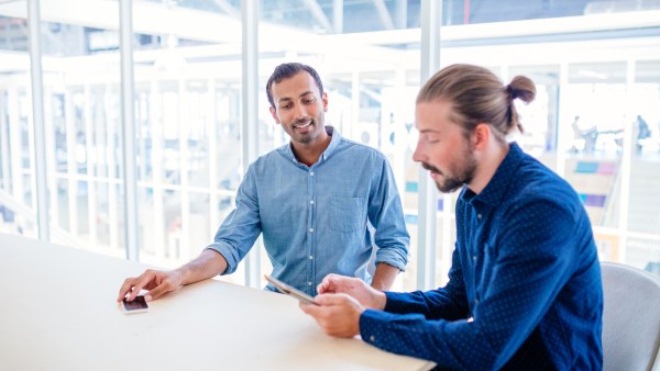 Two male co-workers discuss IRS payment plans in a conference room.