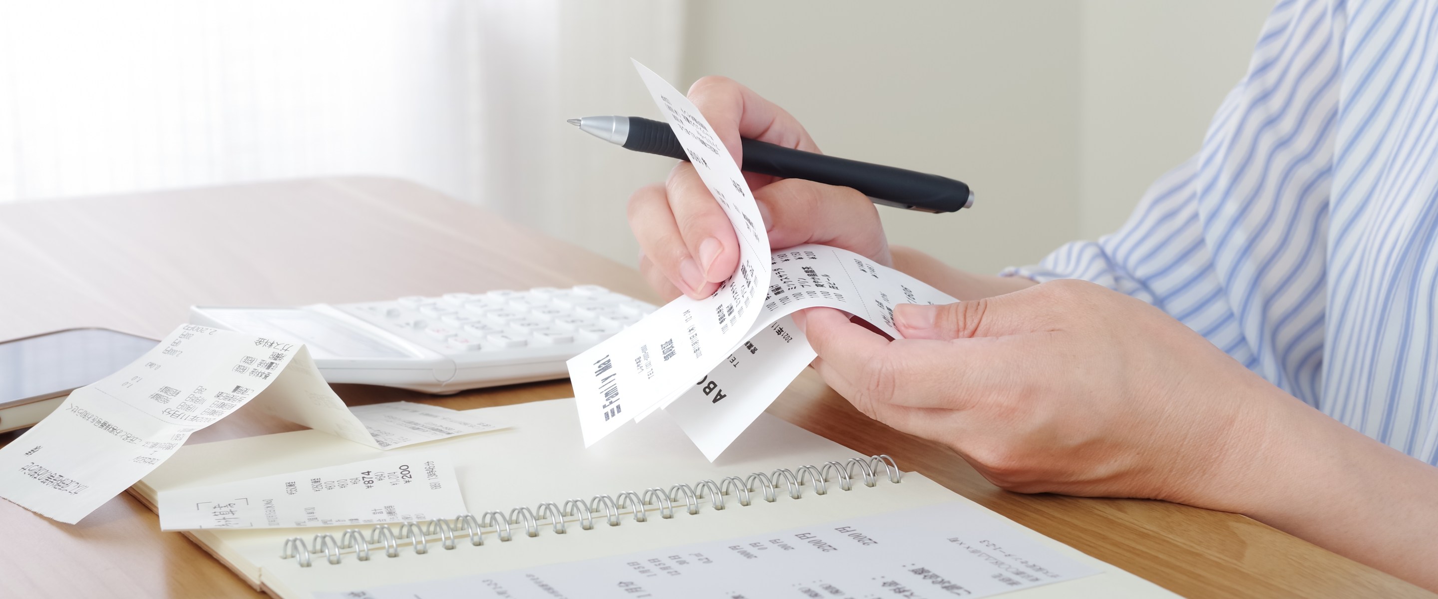 Close-up of someone reviewing receipts and making a list