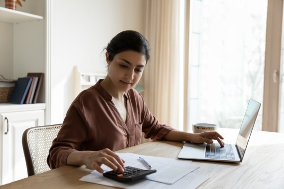 Woman using calculator and laptop.