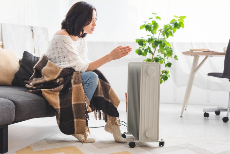 Woman warming herself in front of a space heater.