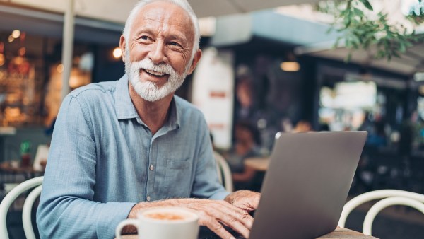 Senior man using laptop to verify his identity.