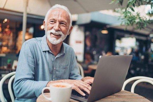 Senior man using laptop to verify his identity.