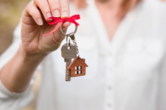 Close-up of a woman holding house keys with a bow on it.