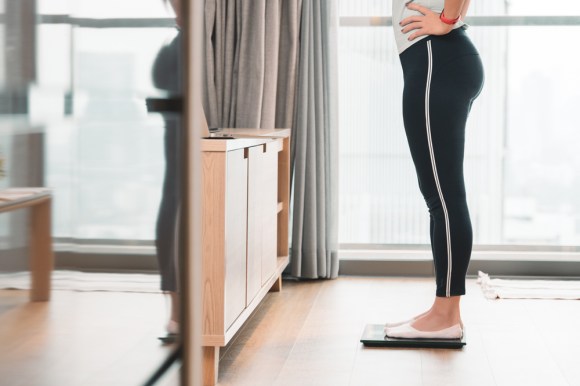 Woman in workout clothes standing on scale.