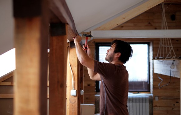 Man working on a house holding hammer. 