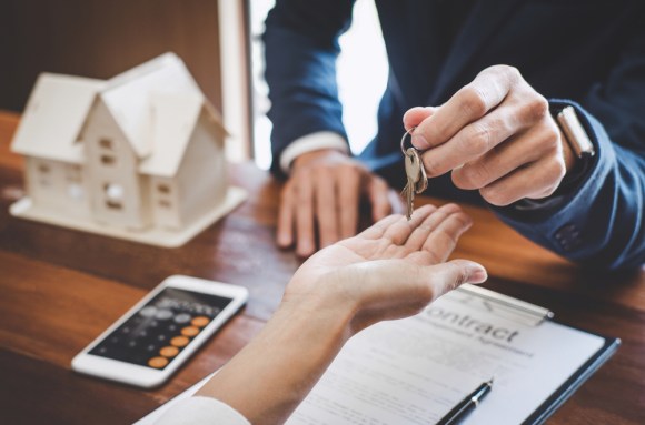 A real estate agent hands keys to a customer after signing a contract.