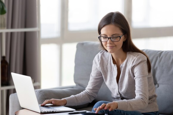 Young woman on her laptop and using a calculator.