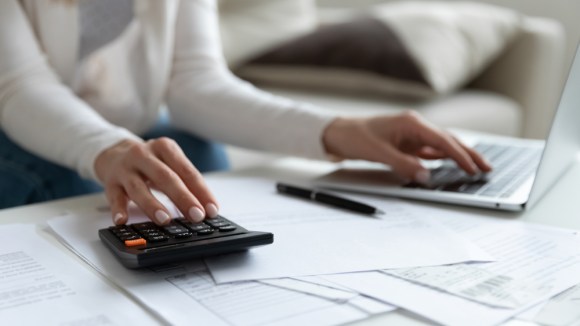 Women doing calculations and using a laptop.