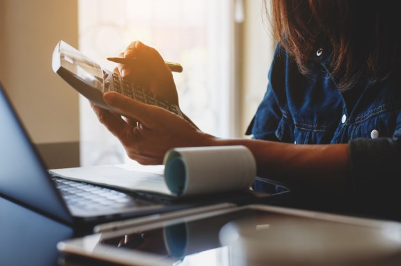 Woman doing payroll holding a calculator.