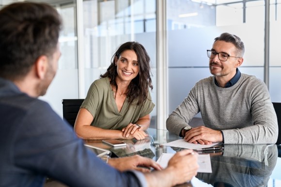 Smiling mature couple meeting with bank manager for investment.