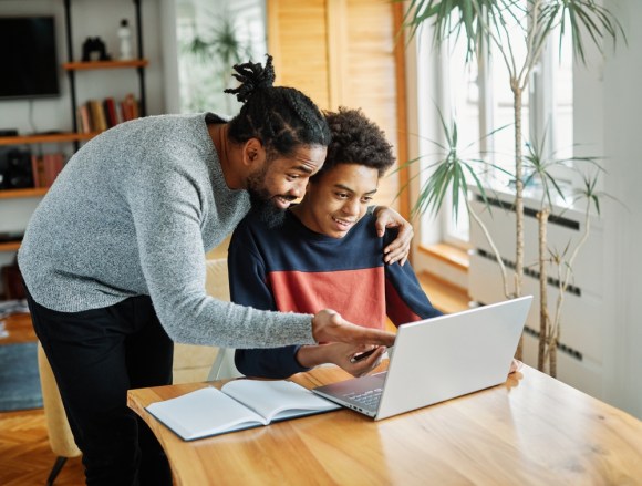 Black father and son working on homework.
