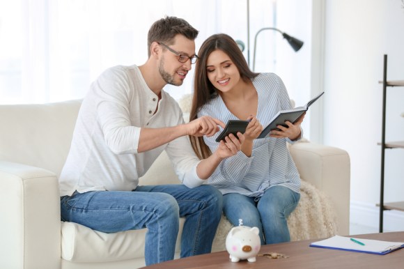 Young couple with a calculator and notebook planning their savings.