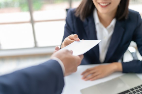 Someone handing a woman a slip of financial paper.