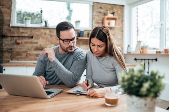 Couple sitting at the kitchen table doing their taxes.
