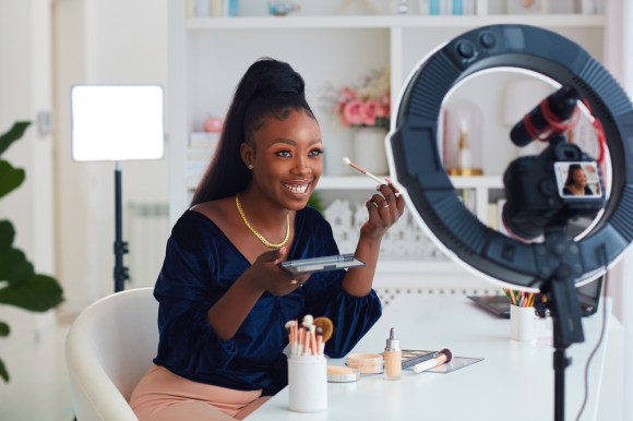 Happy woman influencer recording a beauty tutorial.