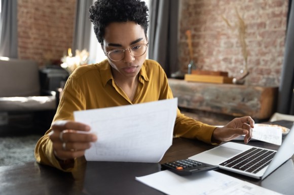 Woman reviewing documents and using a calculator.