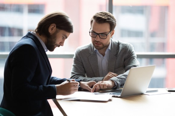 Businessman filling out paperwork with an advisor.