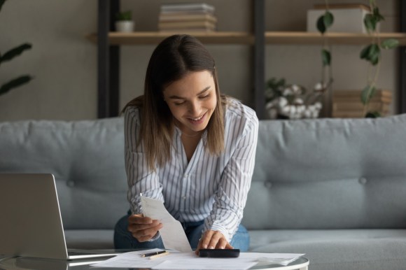 Woman holding receipt while entering info on a calculator.