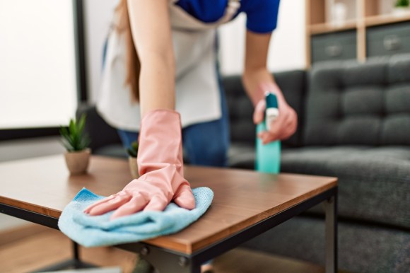 Housekeeper wiping down a wood coffee table.