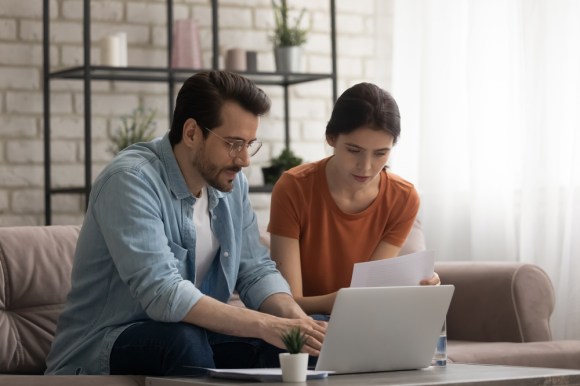 Couple sitting in front of a laptop reading a letter.