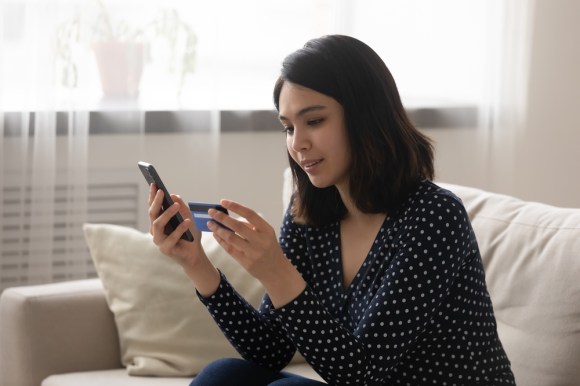 Woman making payment on her phone with a credit card.