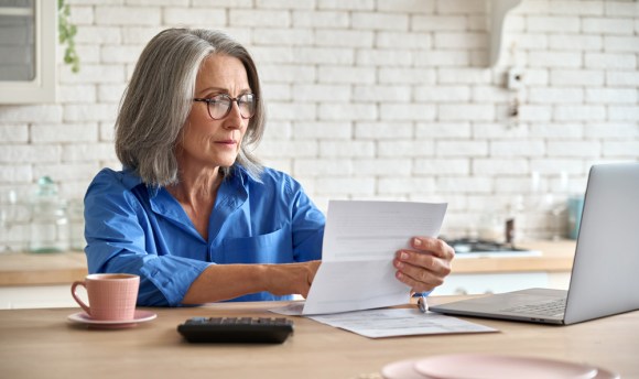 Senior woman reviewing a statement at kitchen table.