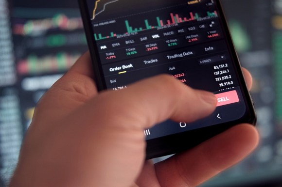 Close-up of a hand holding a phone, showing someone selling securities.