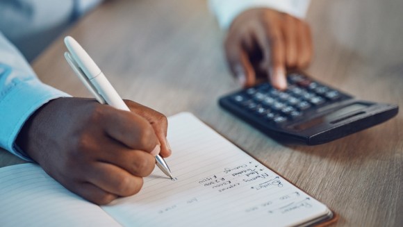 Close-up of someone making a budget and using a calculator.