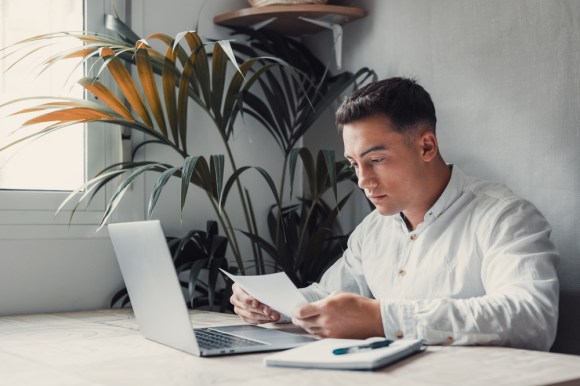 Man reviewing document sitting in front of his laptop.