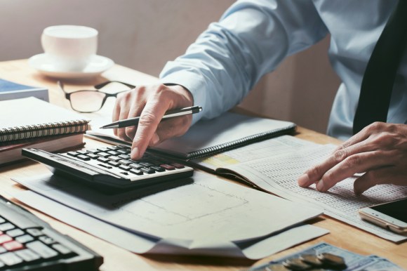 Accountant using a calculator and reviewing numbers.
