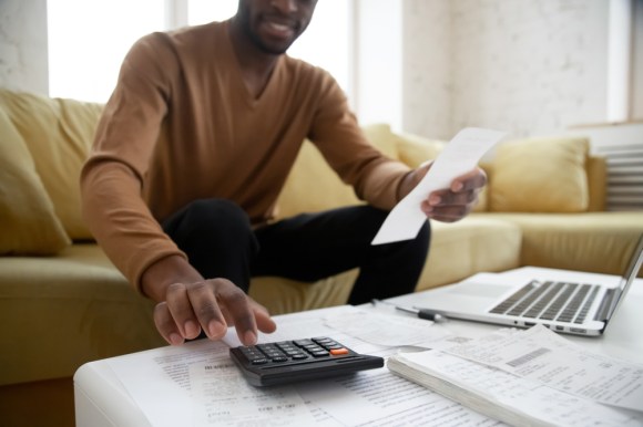 Man sitting on his couch using a calculator.