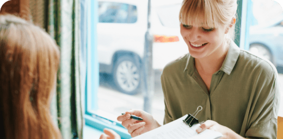 Photo of a woman smiling and explaining tax forms to another person