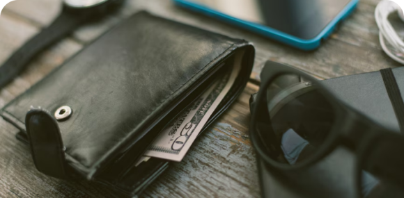 Photo of a black leather wallet, black sunglasses, a black notebook, and a black watch