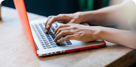 Photo of a user's hands typing on a laptop