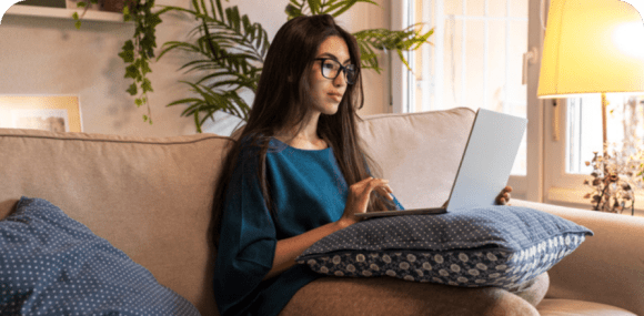 Photo of a woman sitting on her couch and using her laptop